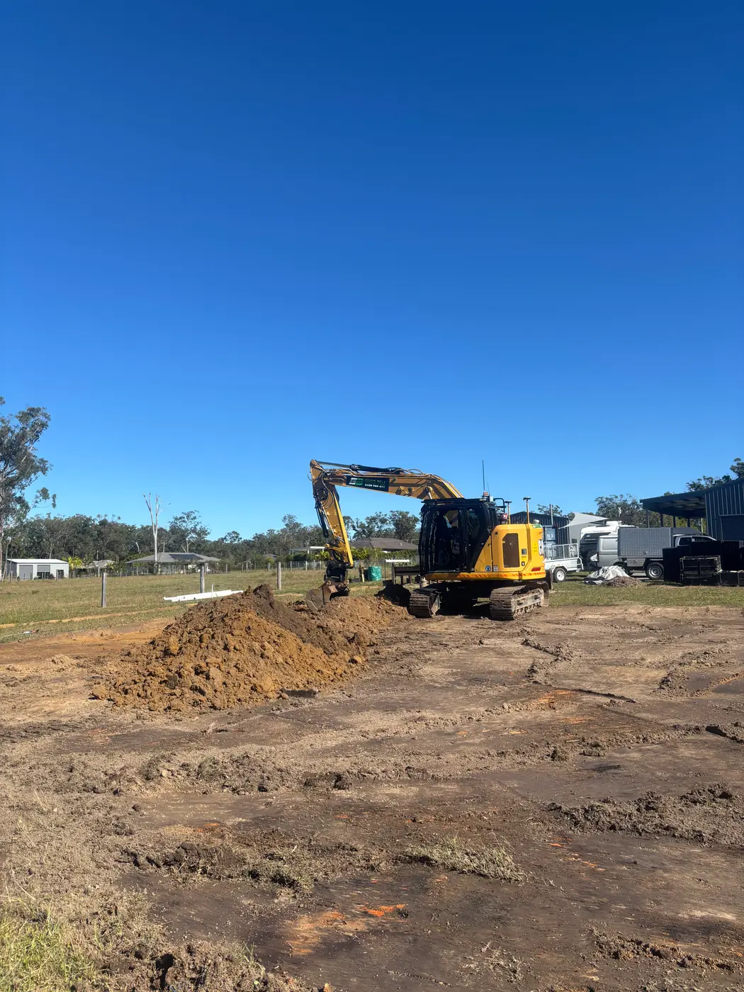 Excavator cutting a building pad on a rural block