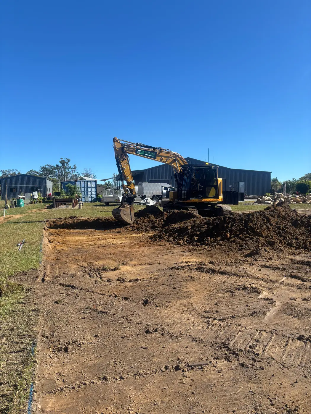Excavator constructing a shed pad on a rural block