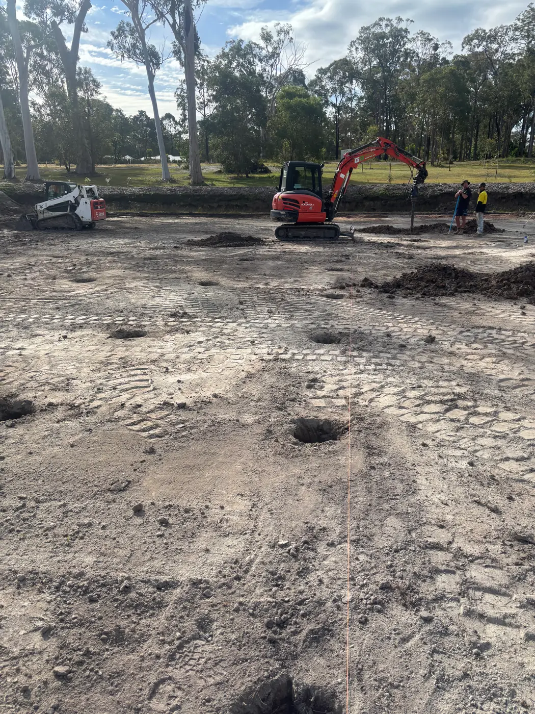 Excavator and skid steer excavating a building pad