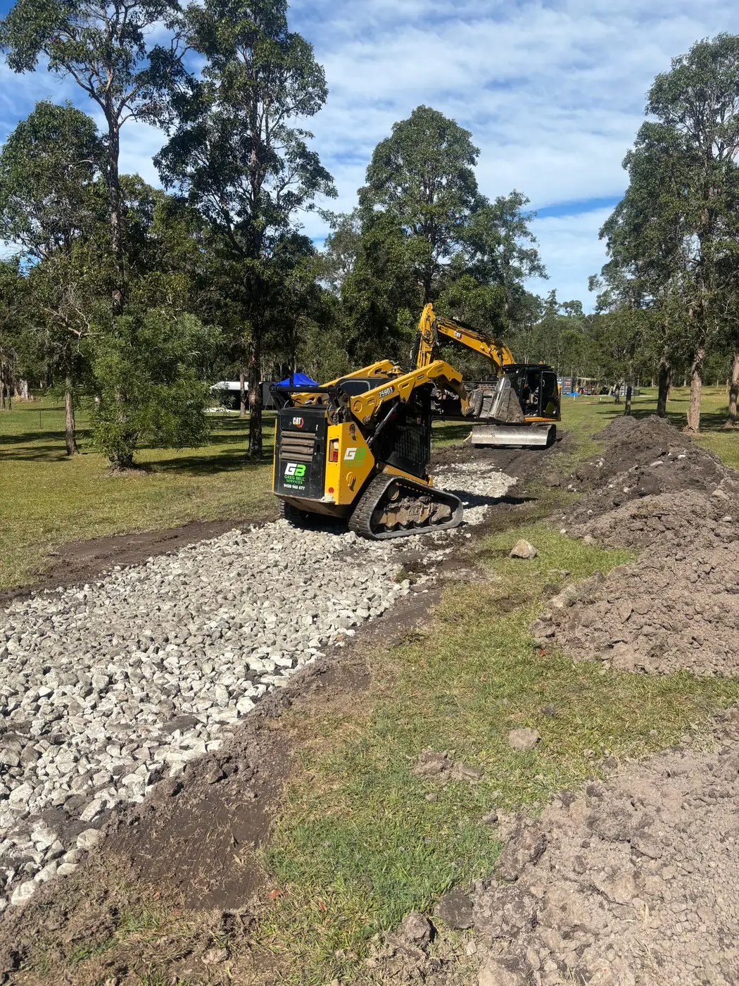 Skid steer spreading gravel on a bushland driveway