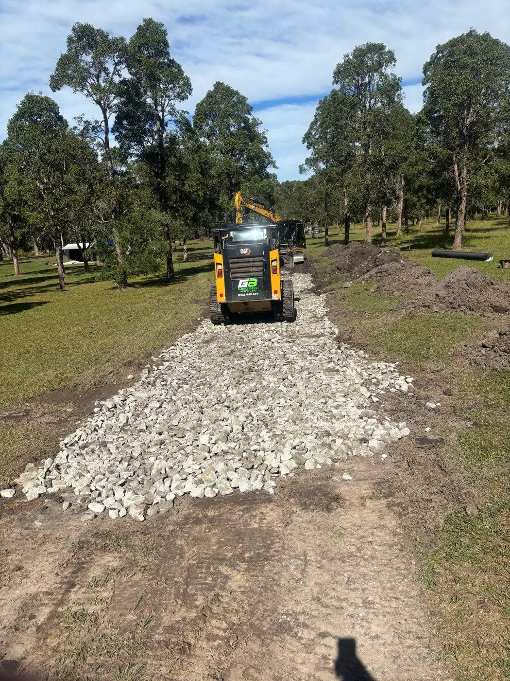 Skid steer spreading delivered roadbase on a rural driveway